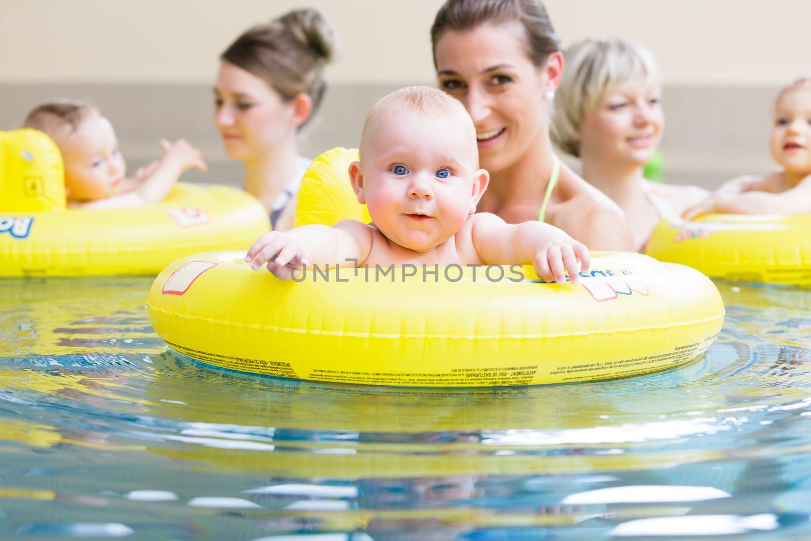 Mums and their children having fun together playing with toys at baby swimming lesson