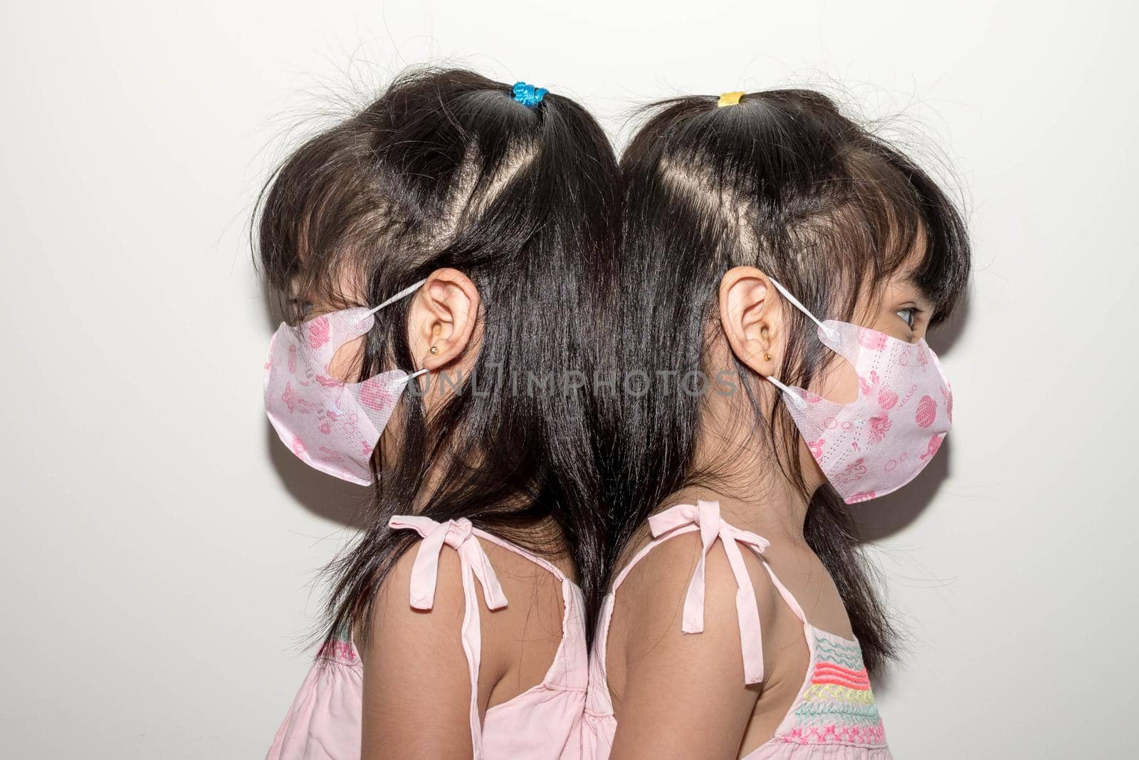 Asian female twins wearing a mask to protect against the Corona virus that can spread through the air by billroque