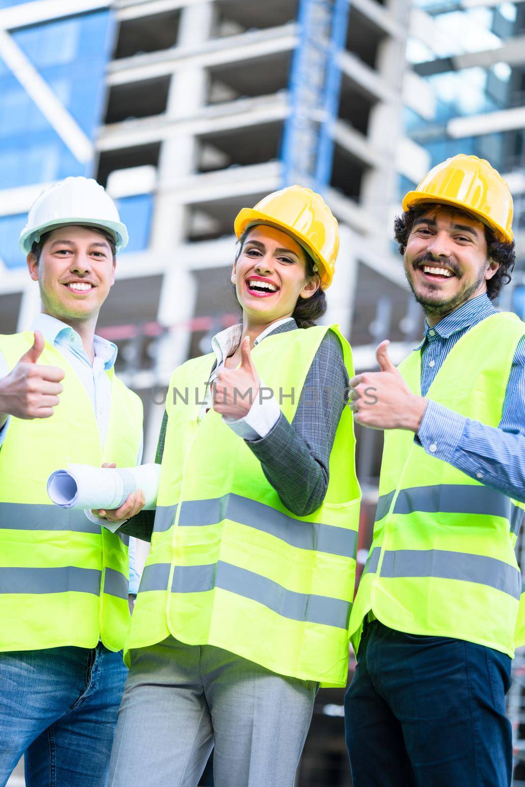 Team of civil engineers and architects at construction site giving thumbs up gesture and saying OK