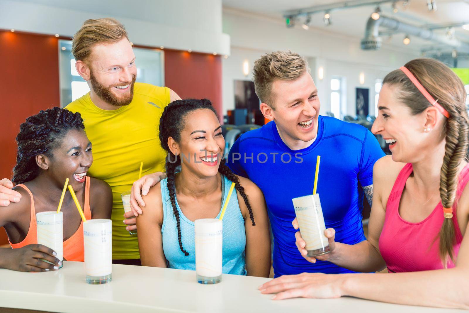 Multi-ethnic group of cheerful friends drinking protein shakes by Kzenon