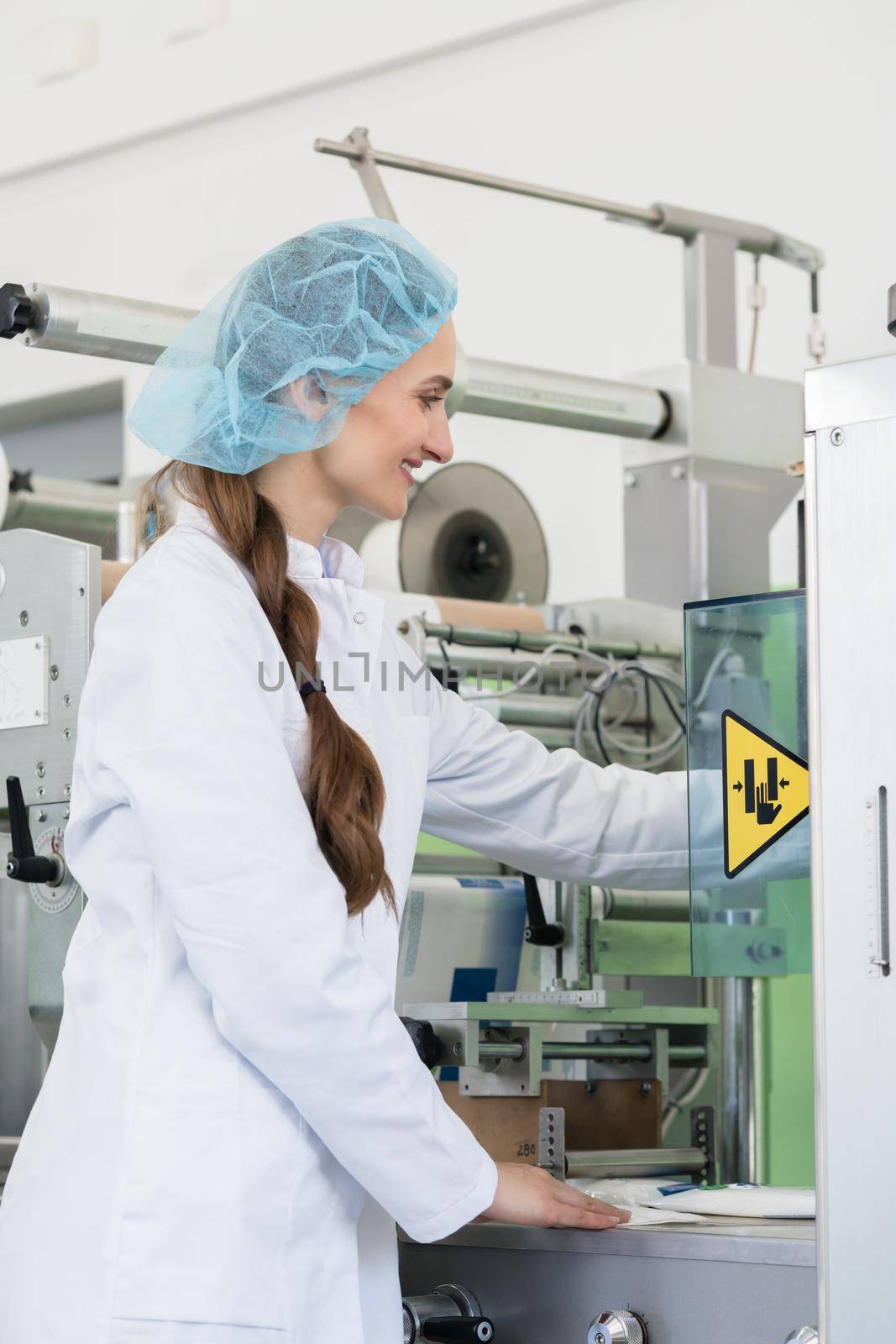 Close-up of the hand of a female manufacturing engineer adjusting the settings of an industrial machine during work in a modern cosmetics factory