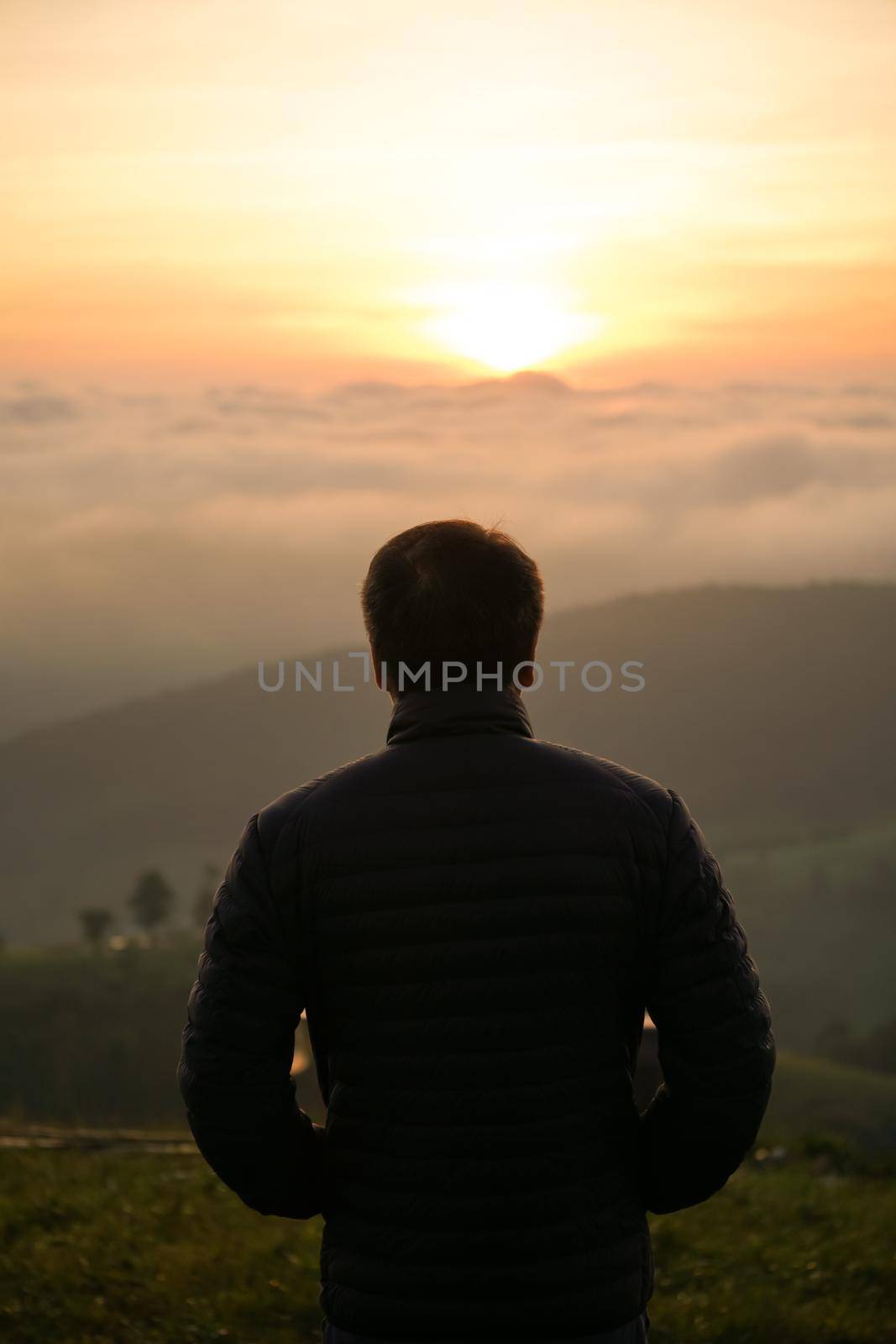 man watching sunrise alone at hilltop