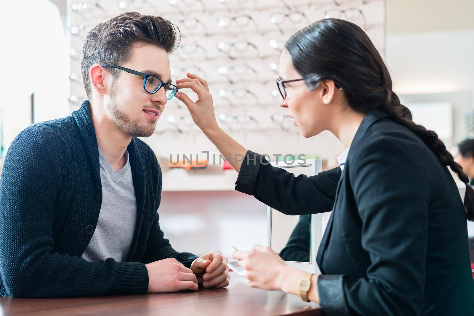 Man in optician shop getting advice from saleswoman by Kzenon