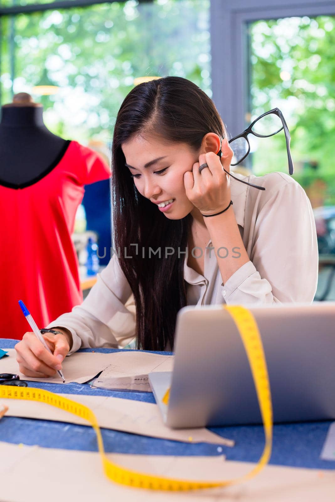 Asian fashion designer preparing drafts for cut-outs in studio