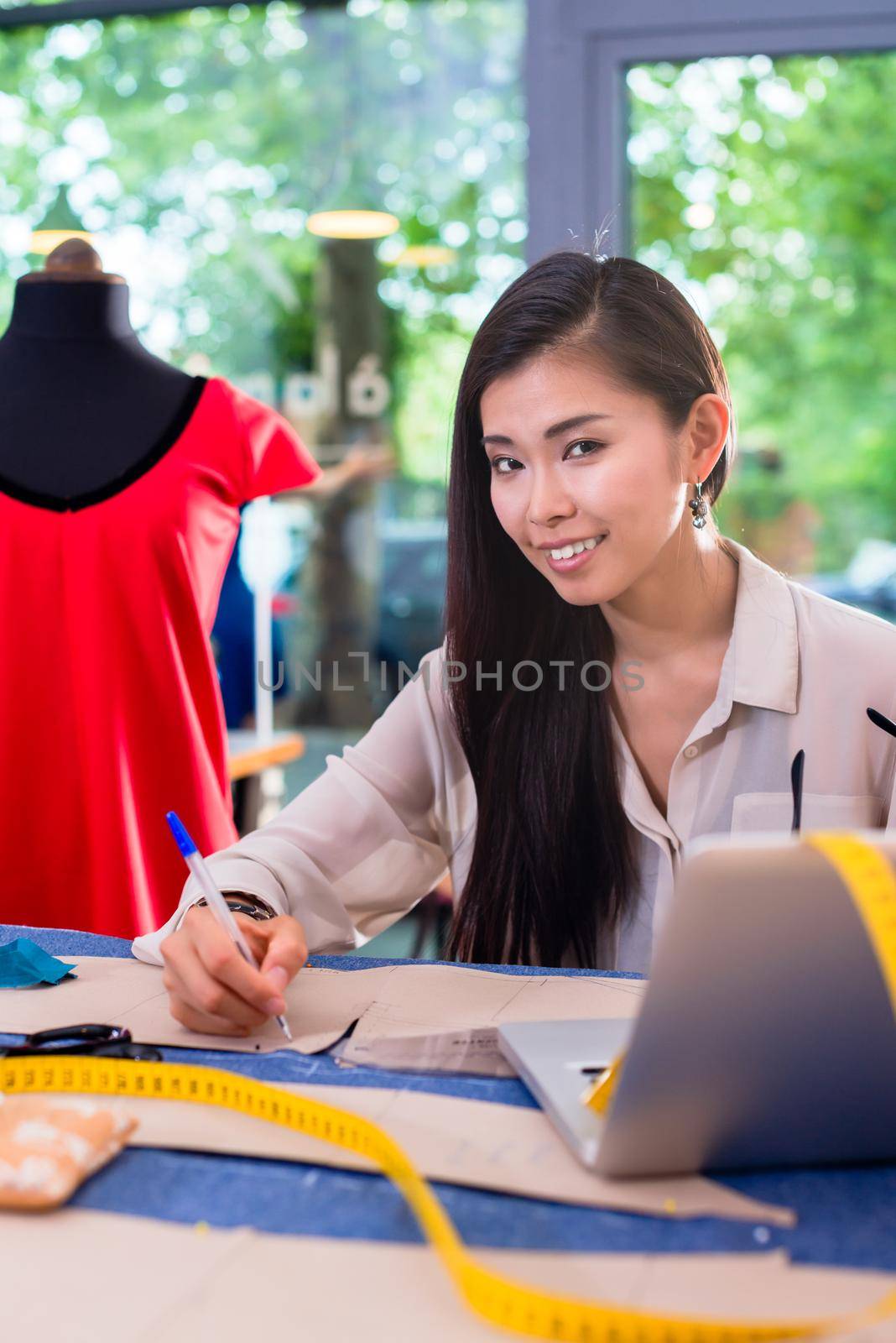 Asian fashion designer preparing drafts for cut-outs for her new collection