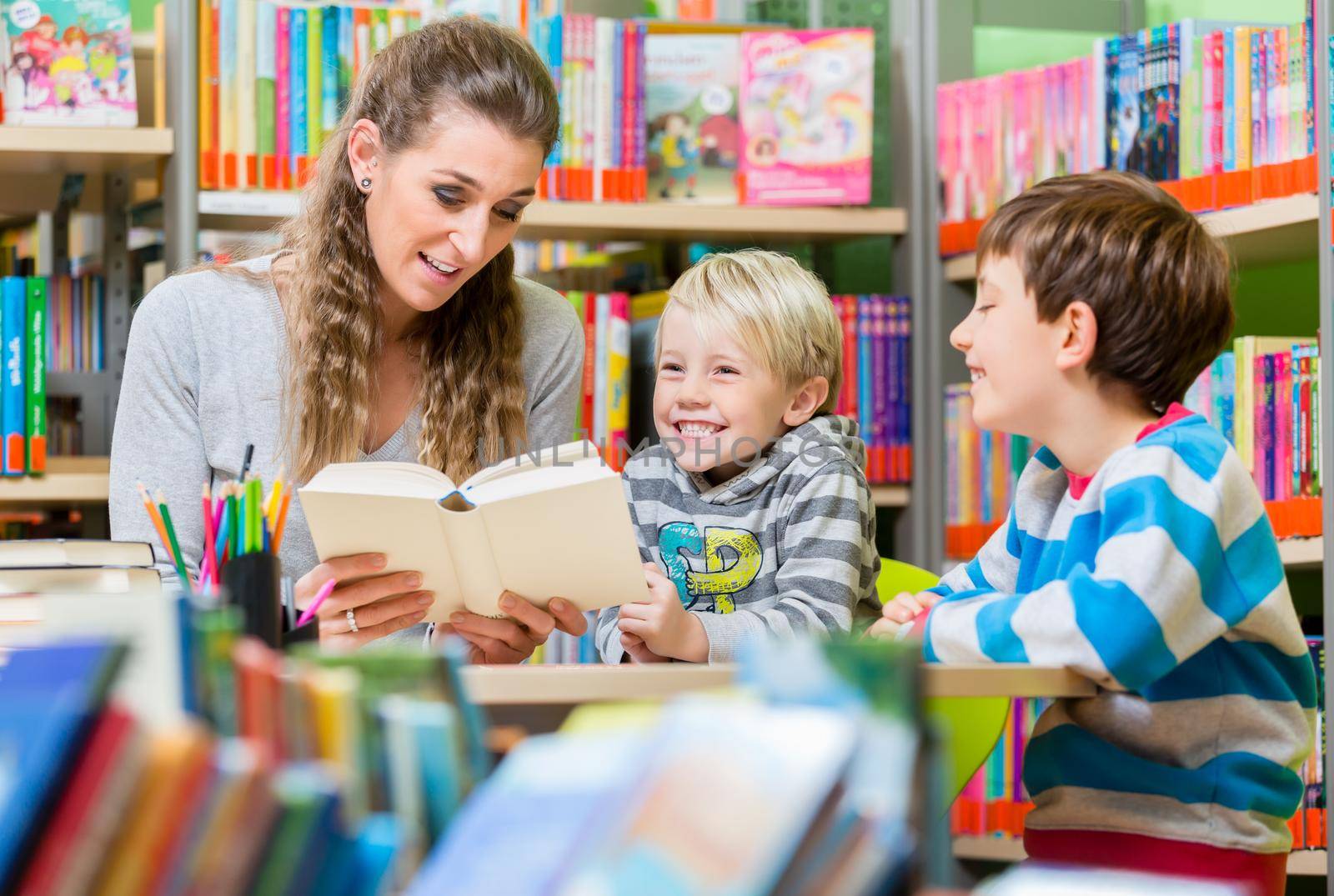 Family reading books in the library by Kzenon