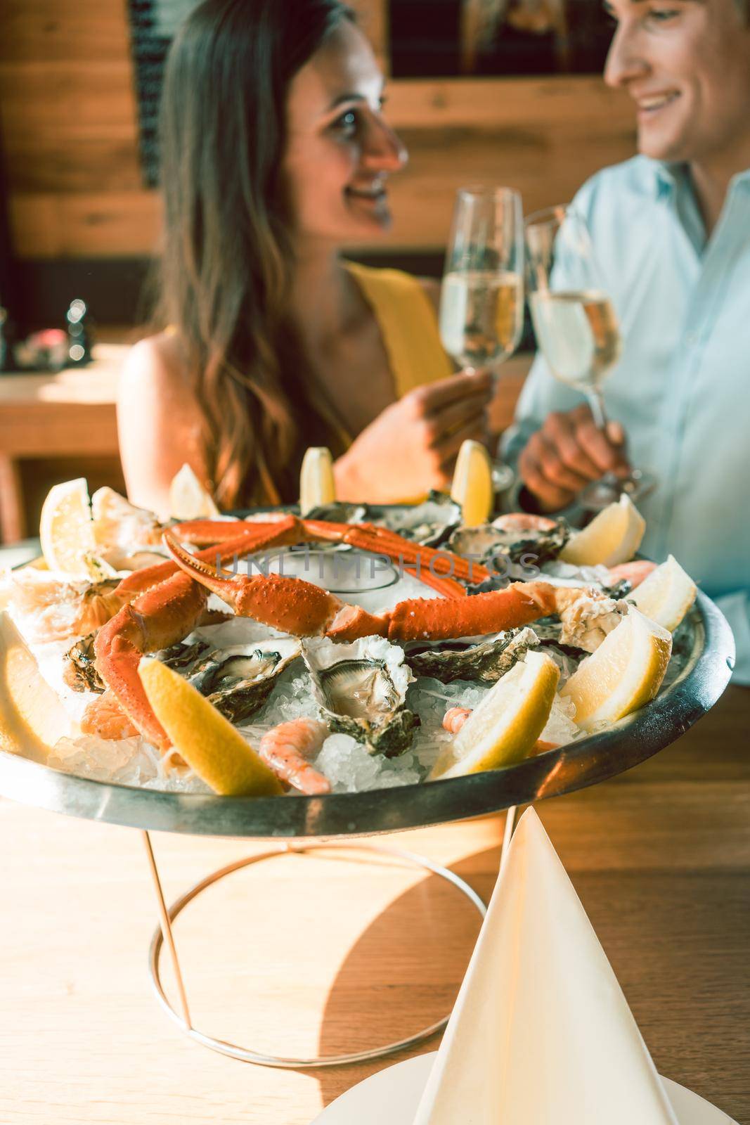 Close-up of fresh oysters and crabs served on ice with slices of lemon at the table of a romantic young couple eating at restaurant