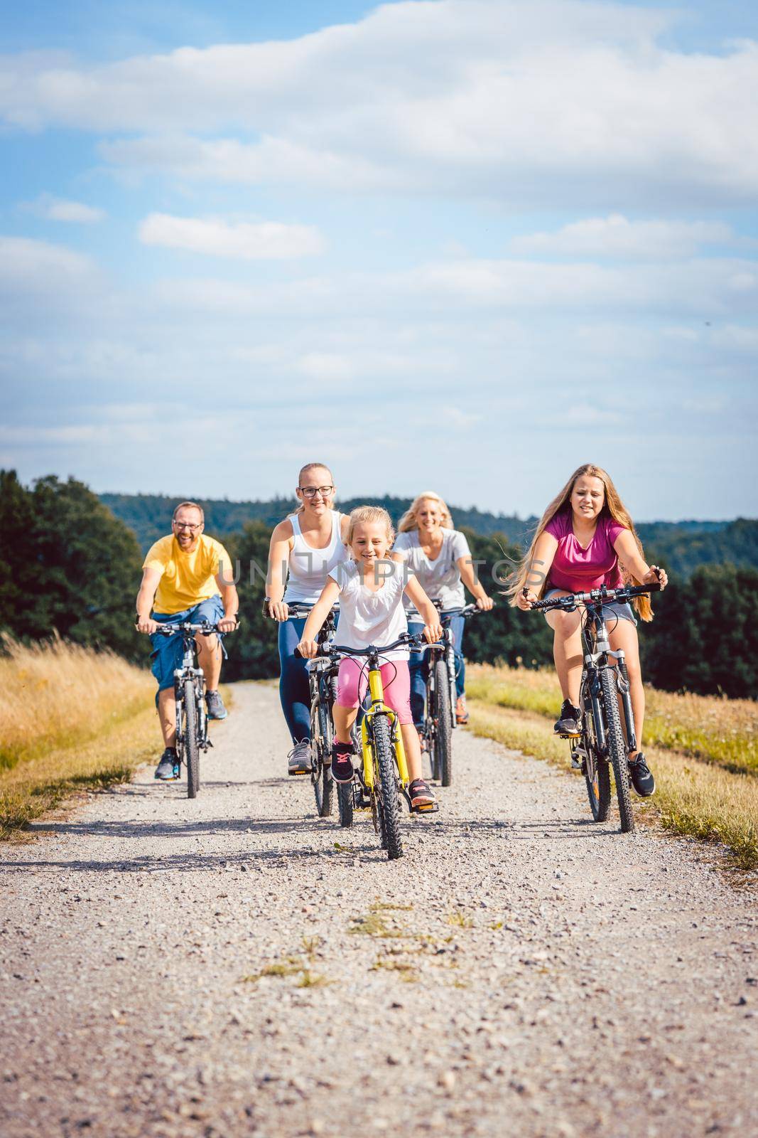 Family riding their bicycles on afternoon in the countryside by Kzenon