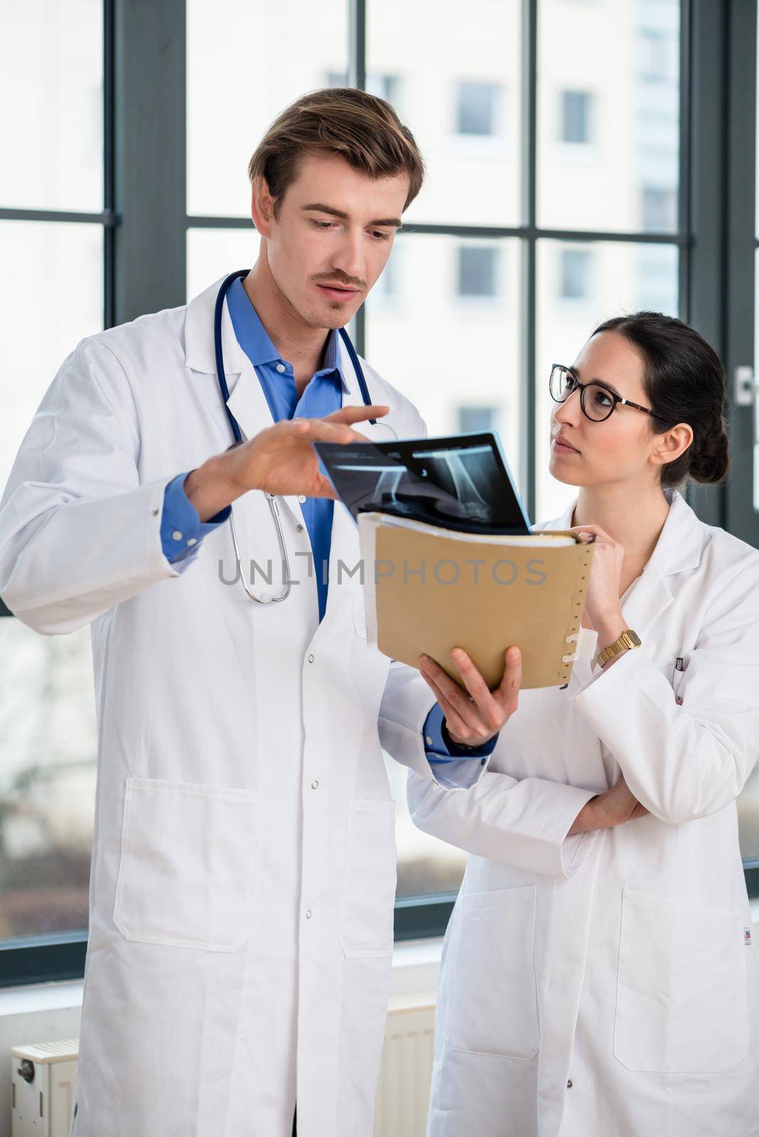 Experienced male physician and his female colleague interpreting the radiograph of the knee of a patient in a modern orthopedic clinic