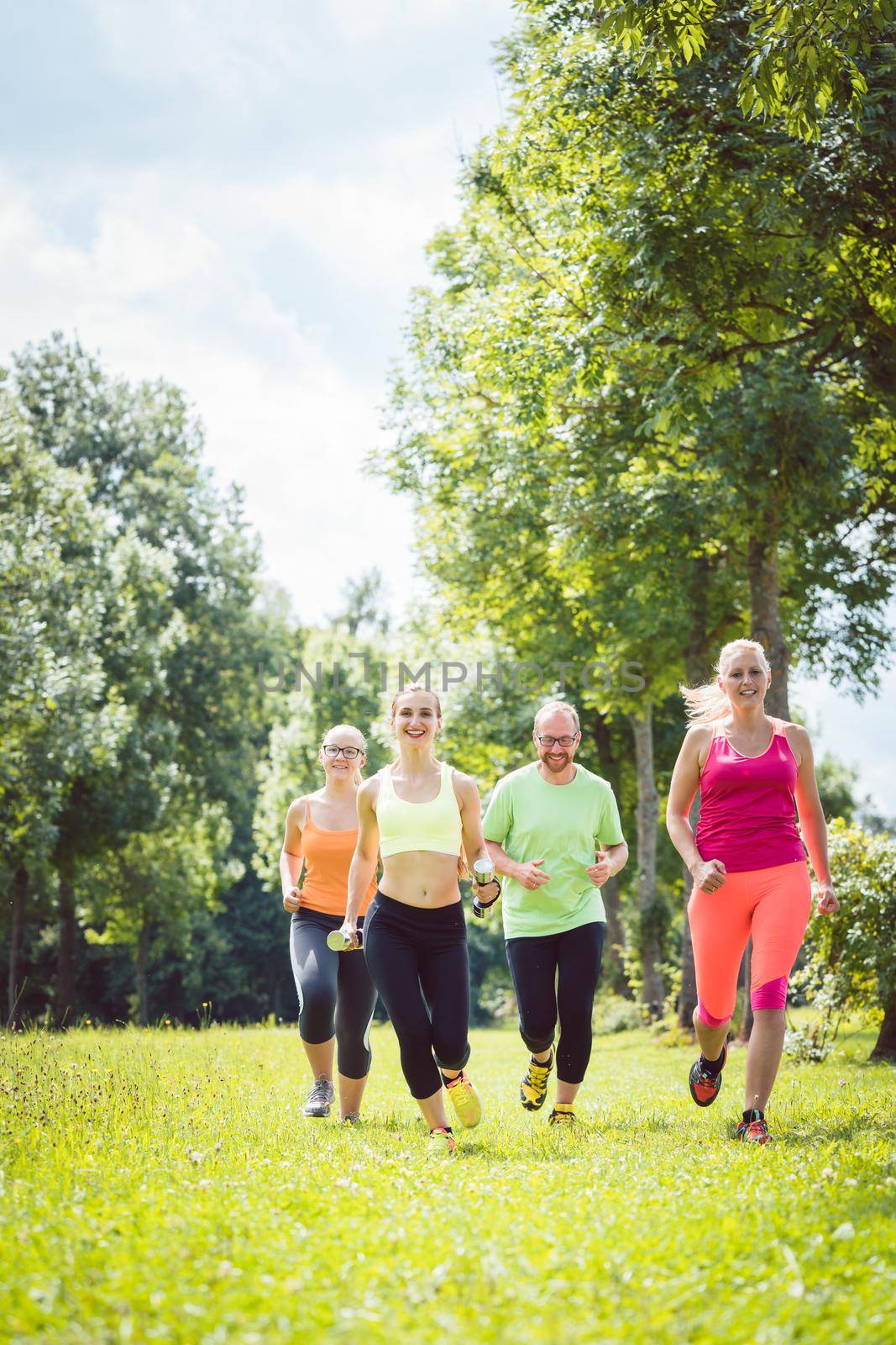 Family with personal Fitness Trainer jogging by Kzenon