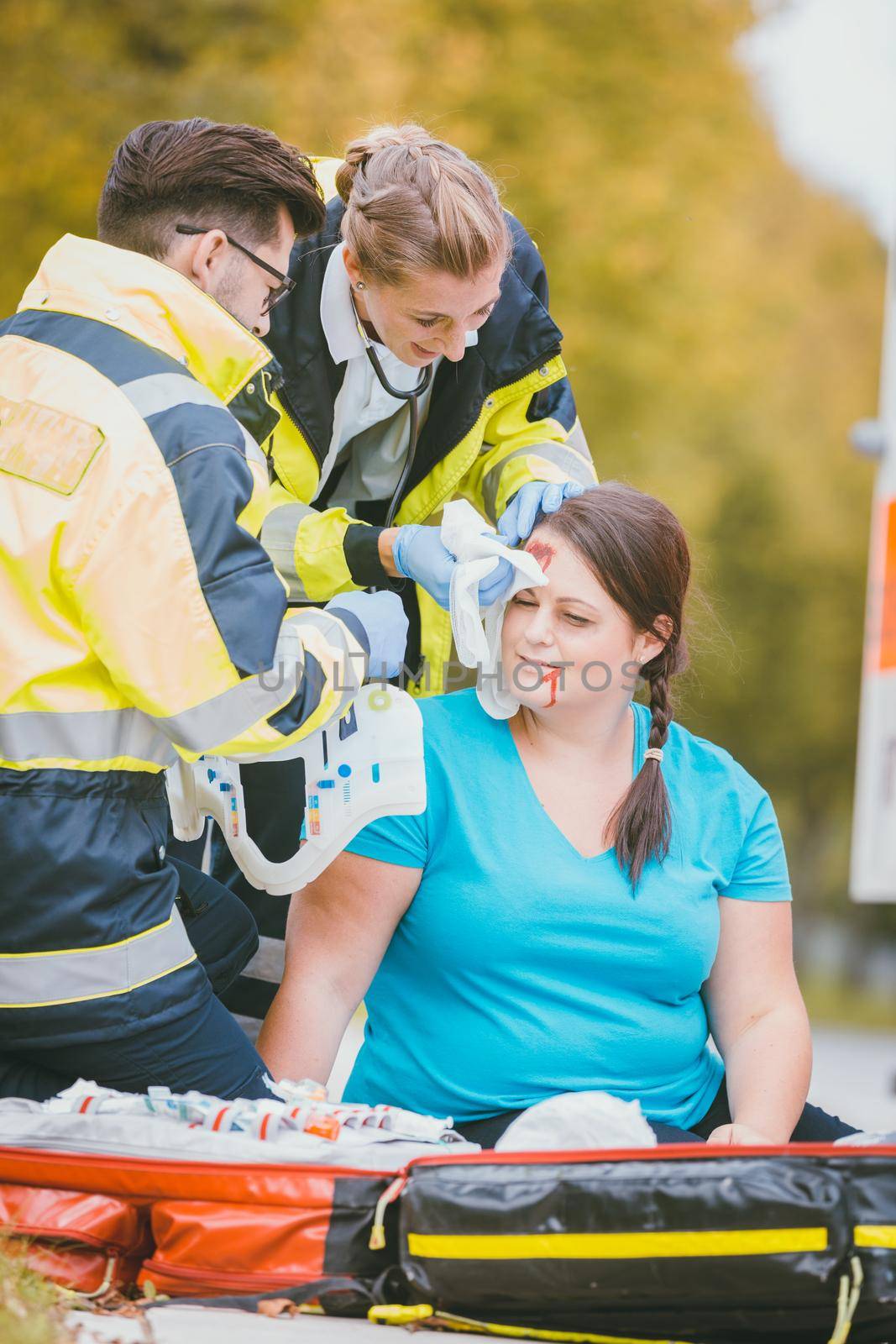 Emergency medics dressing head wound of injured woman after accident