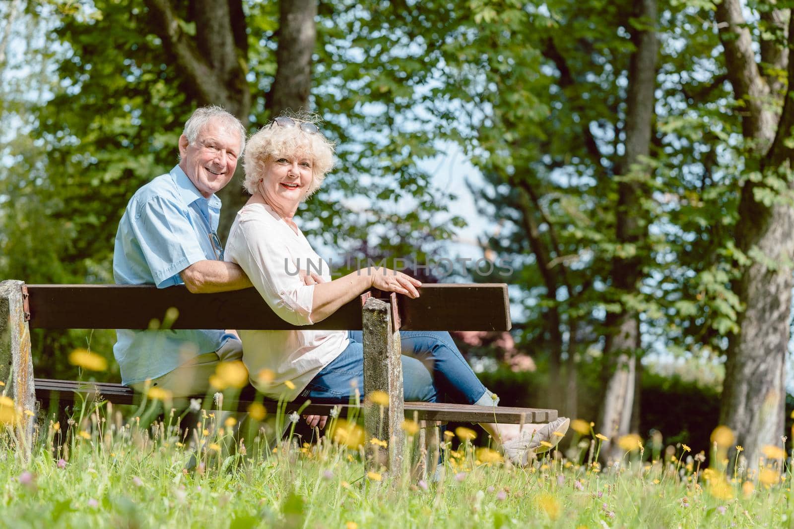 Romantic elderly couple sitting together on a bench in a tranquil day by Kzenon