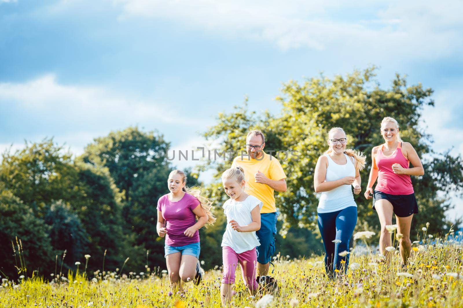 Family running on a meadow for sport by Kzenon