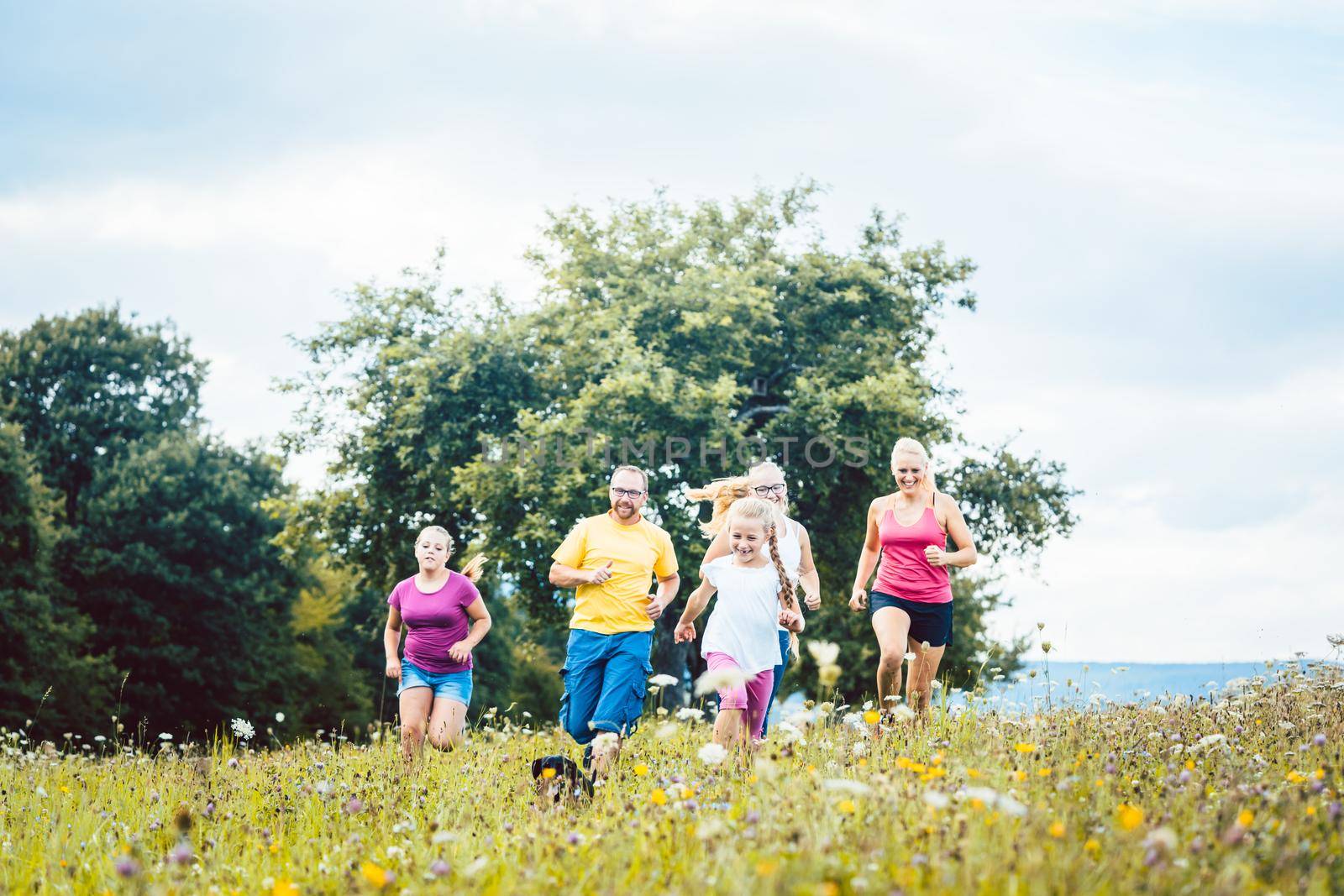 Family running on a meadow for sport by Kzenon
