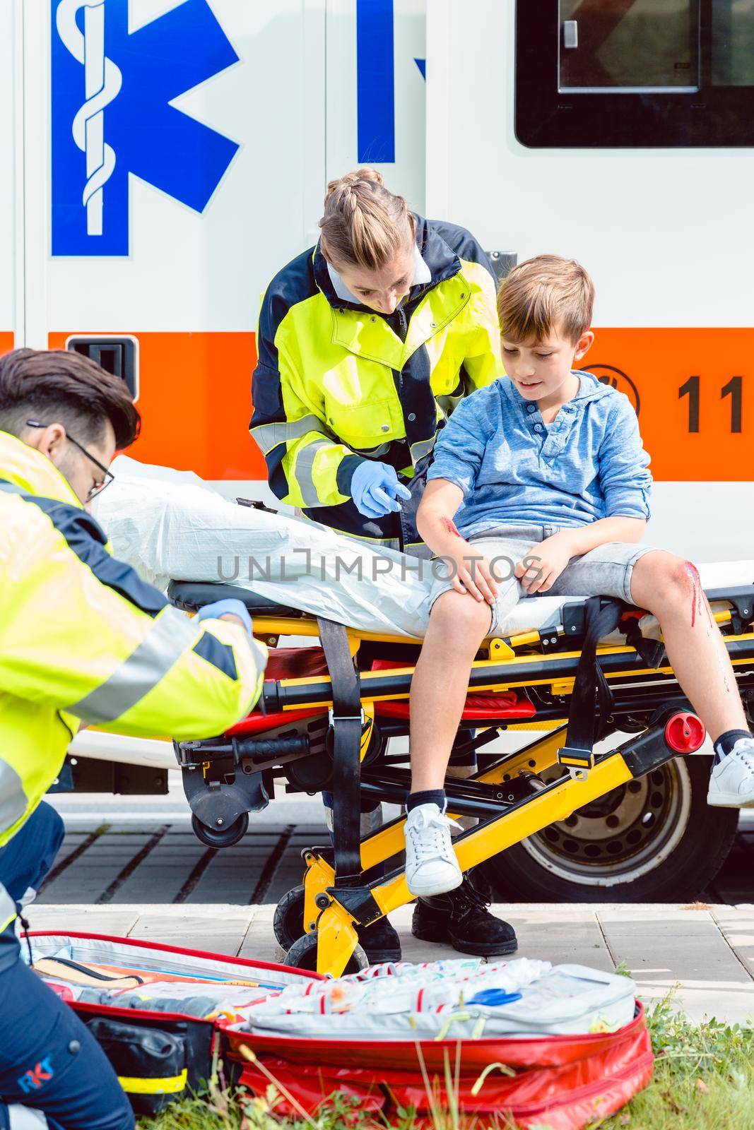 Emergency doctors caring for accident victim boy sitting on stretcher