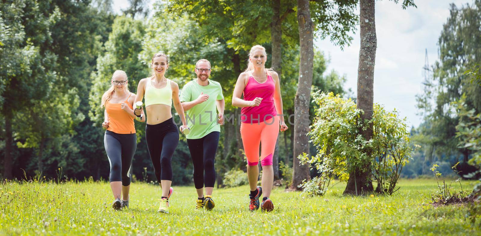 Family with personal Fitness Trainer jogging on a meadow