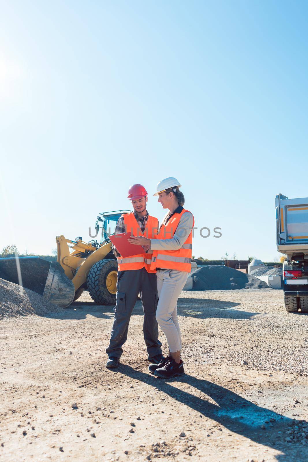 Worker and engineer on earthworks construction site planning by Kzenon