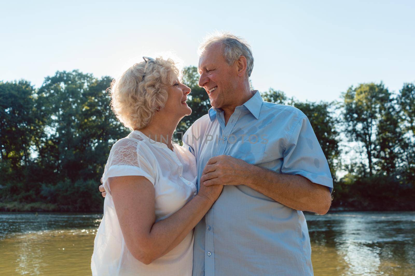 Low-angle side view portrait of a romantic senior couple in love enjoying a healthy and active lifestyle outdoors in summer