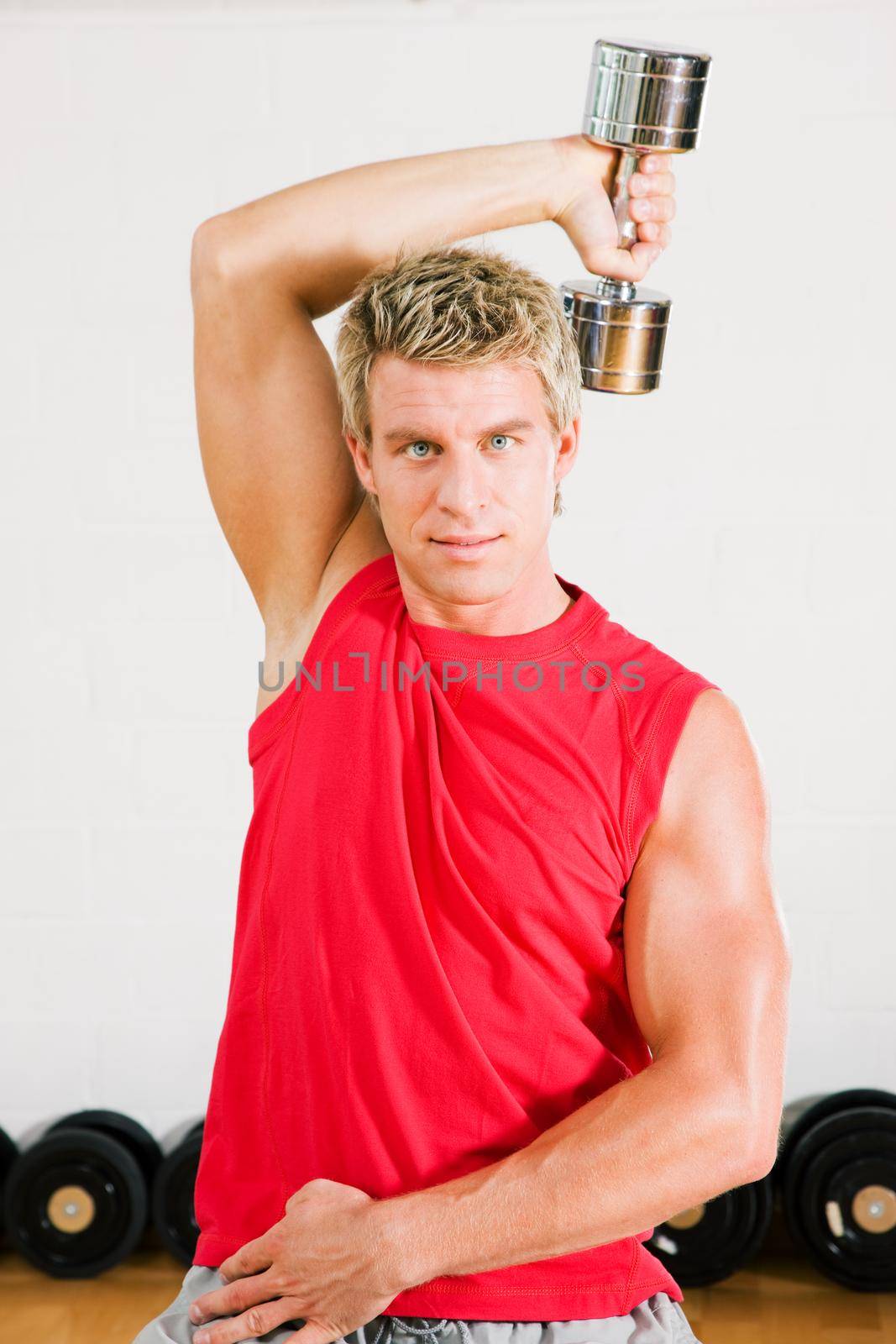 Young sportive man working out using dumbbells in the gym