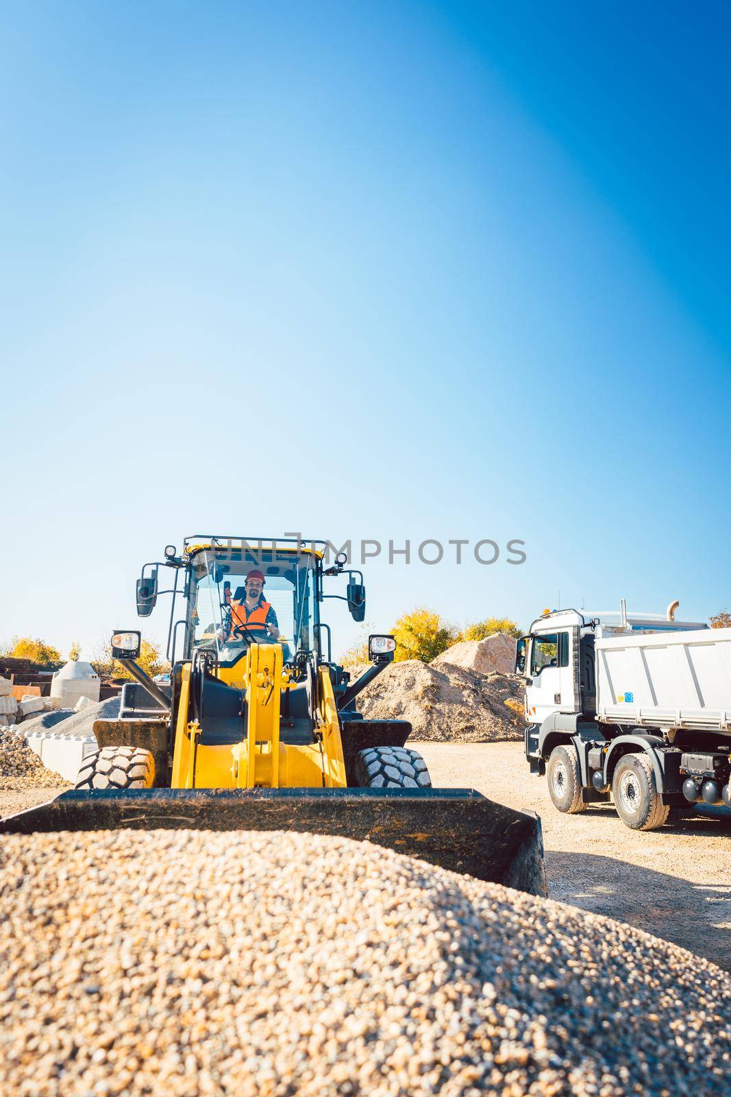 Construction workers doing earthworks with wheel loader by Kzenon