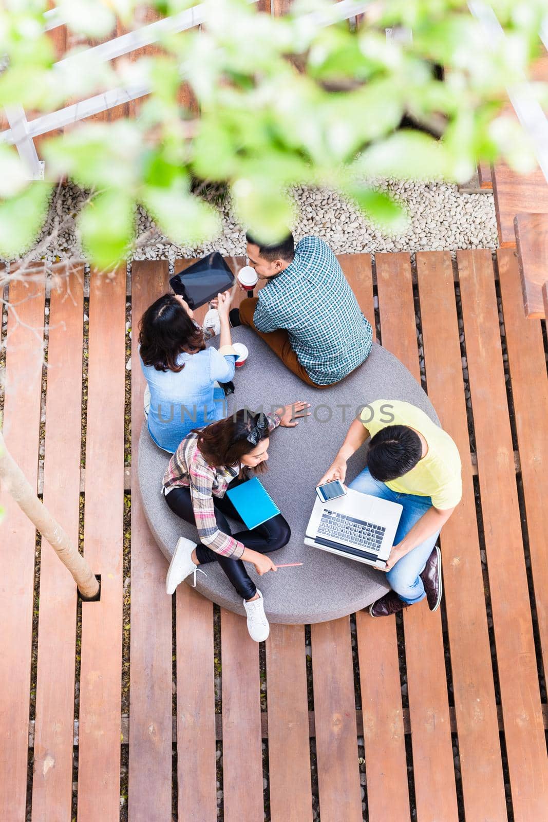 High angle view of four young employees using modern wireless technology while working outdoors on different projects