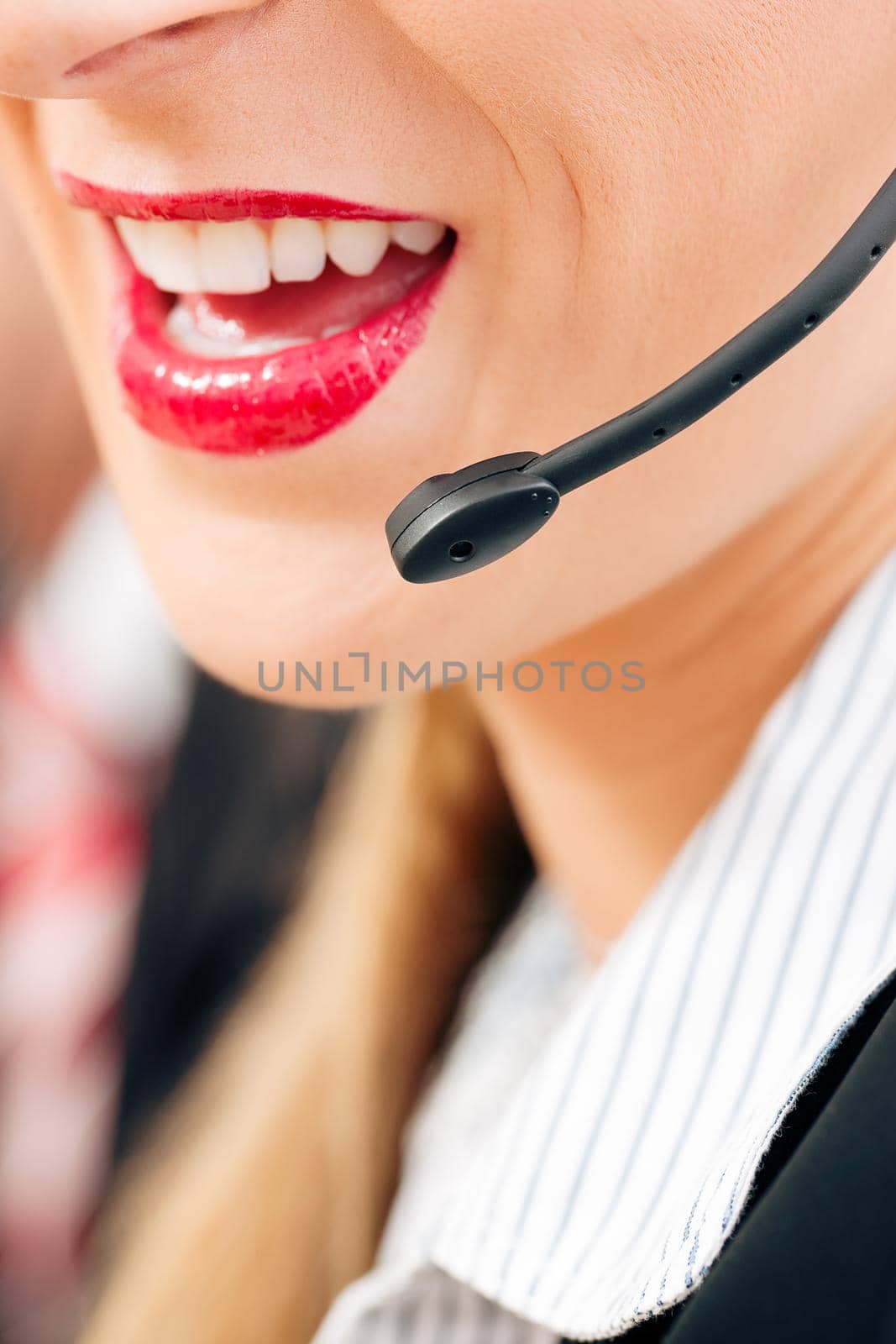 Portrait of a friendly female call center operator (only parts of face) rendering customer service