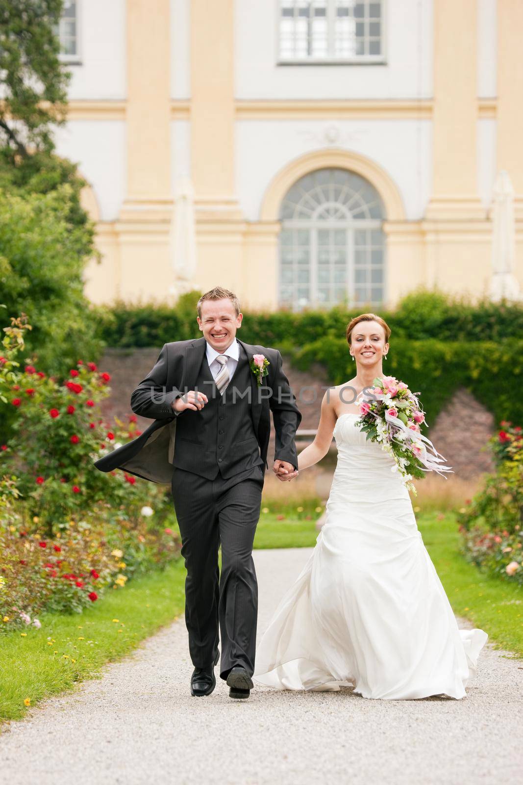 Newlywed couple - bride and groom - in a park running into a future (child, dissent, divorce etc.)