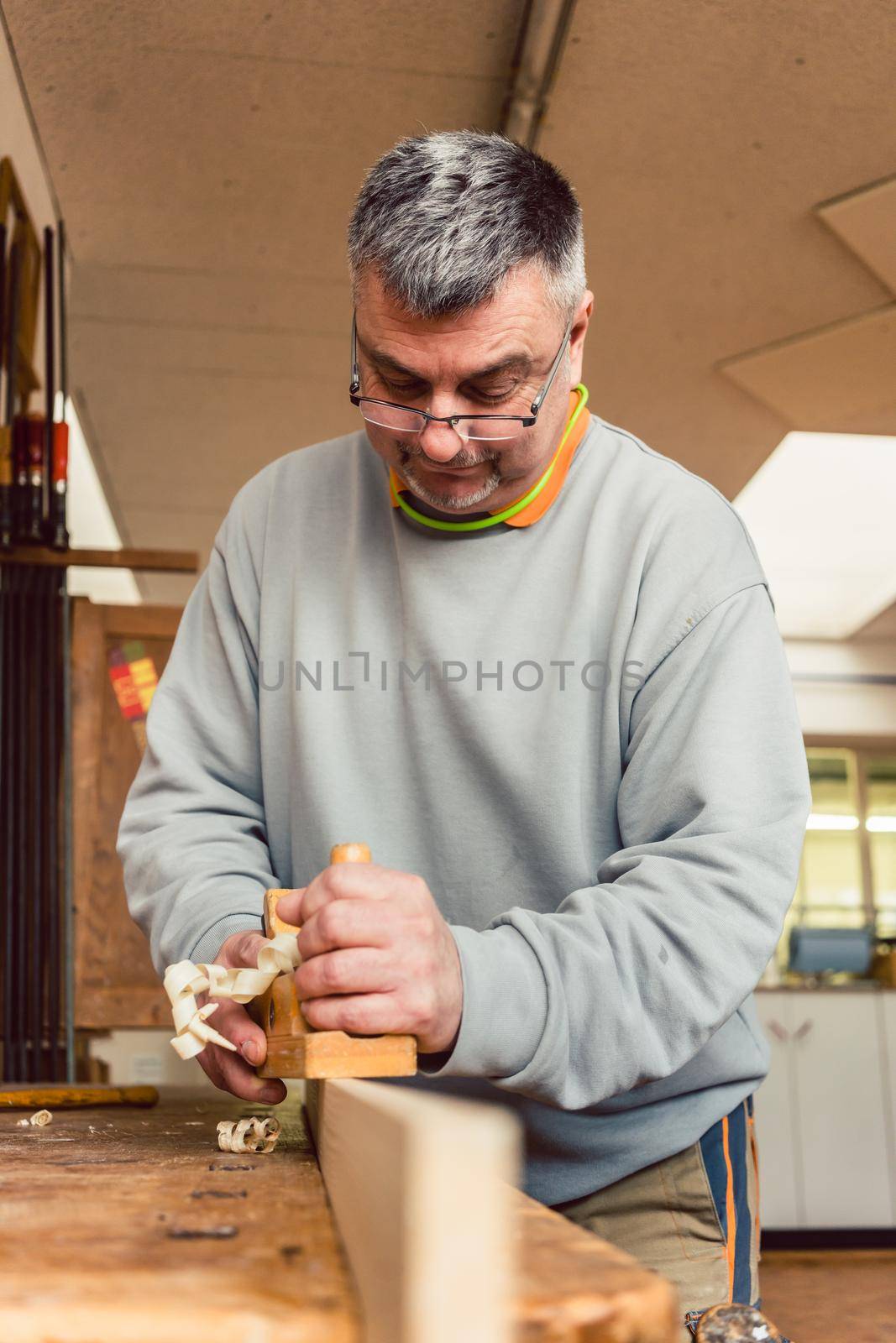Experienced carpenter planing a board in his workshop