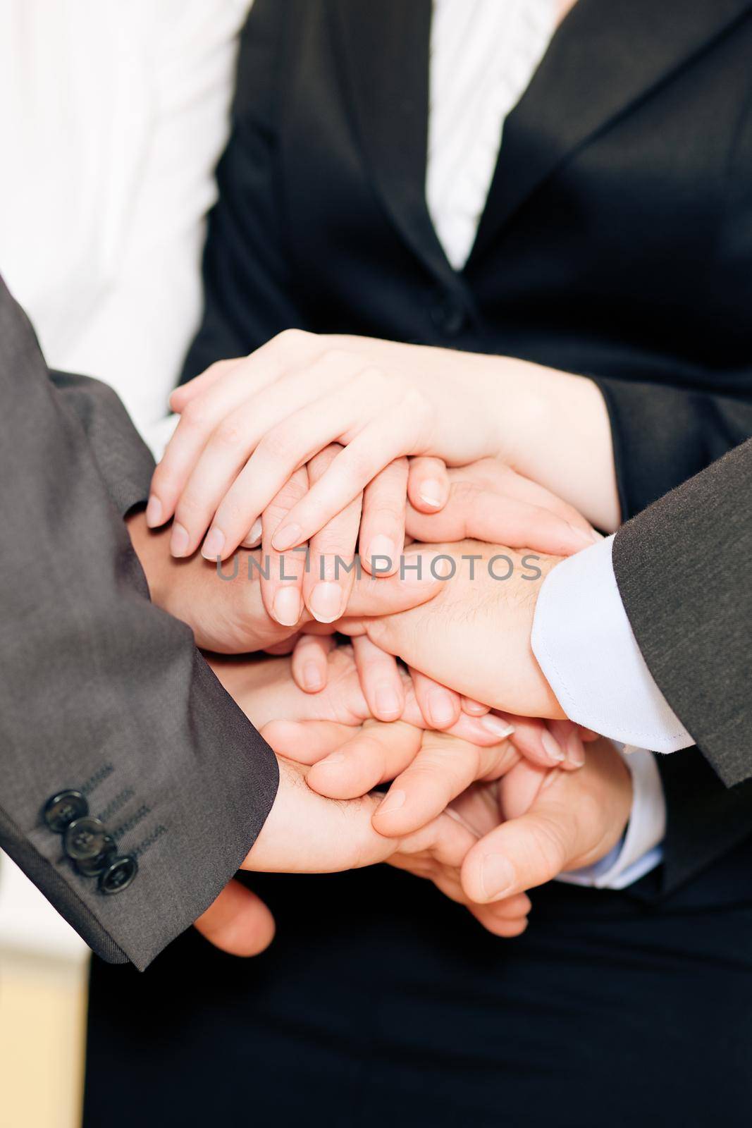 Businesspeople stacking their hands together - a strong symbol for their willingness and determination to reach a shared goal