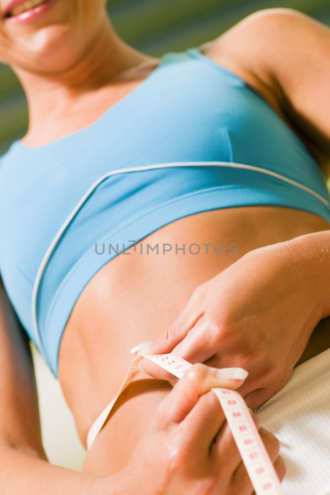 Woman measuring her waist with a respective tape