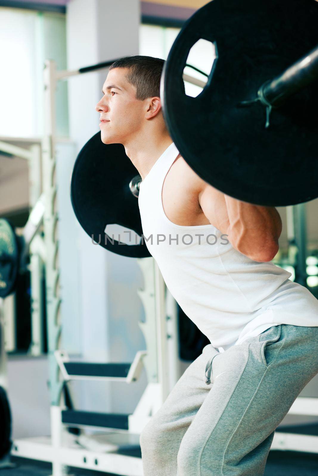 Man lifting weights in gym by Kzenon