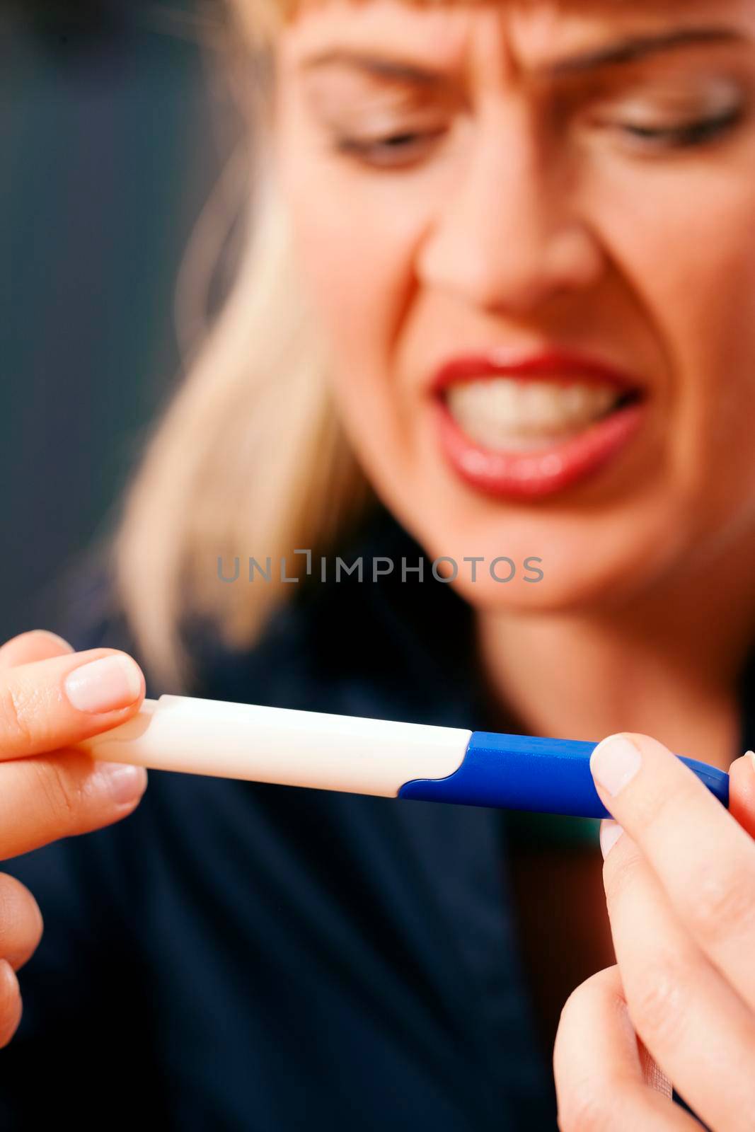 woman doing pregnancy test being unhappy by Kzenon
