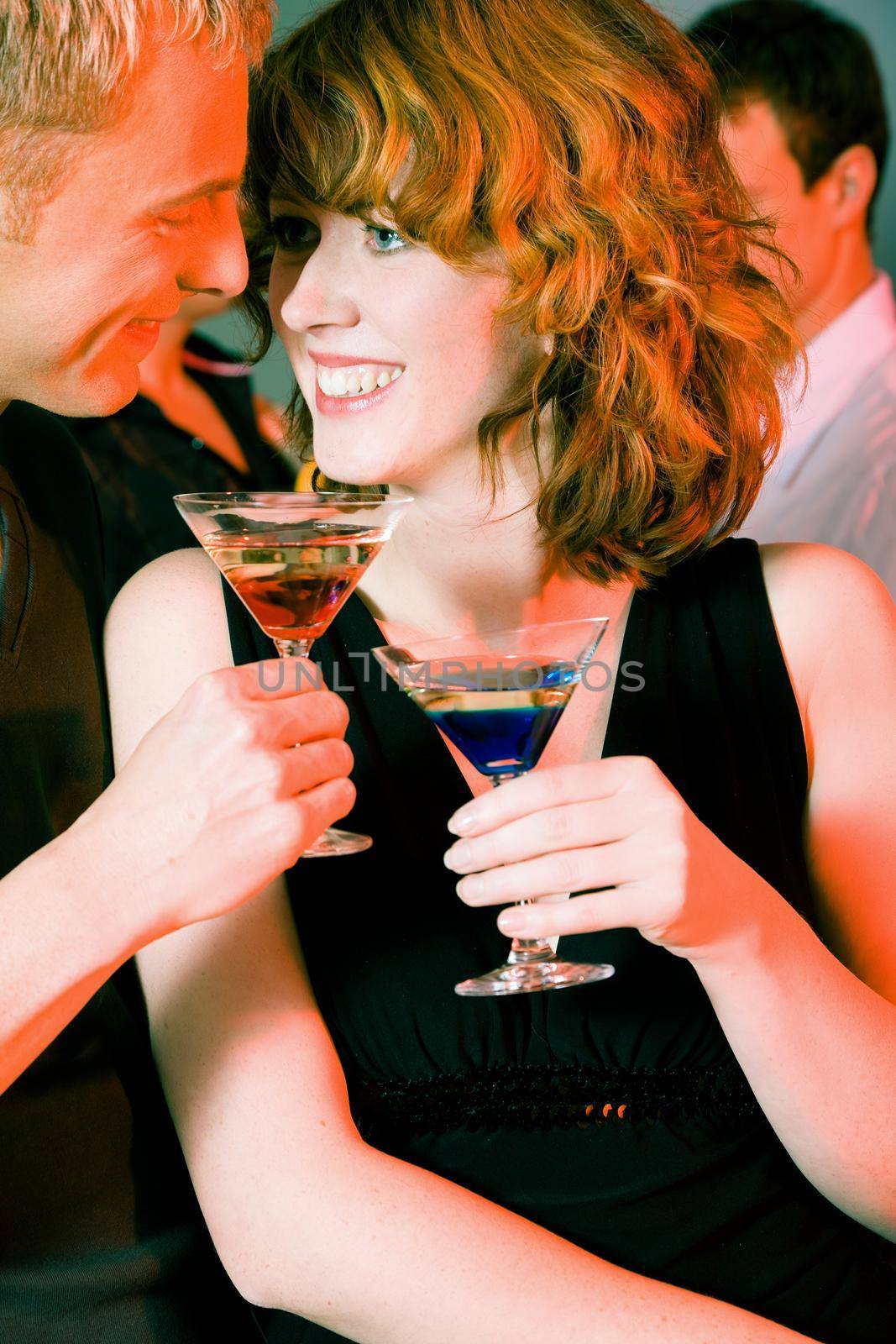 Couple flirting very obviously in a bar or at a club, cocktail drinks in front of them