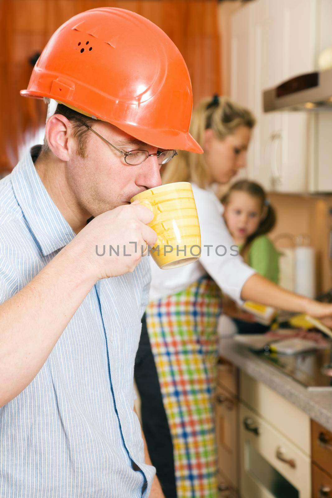 Construction worker with hardhat and father of a family having a morning cup of coffee before heading for his workplace