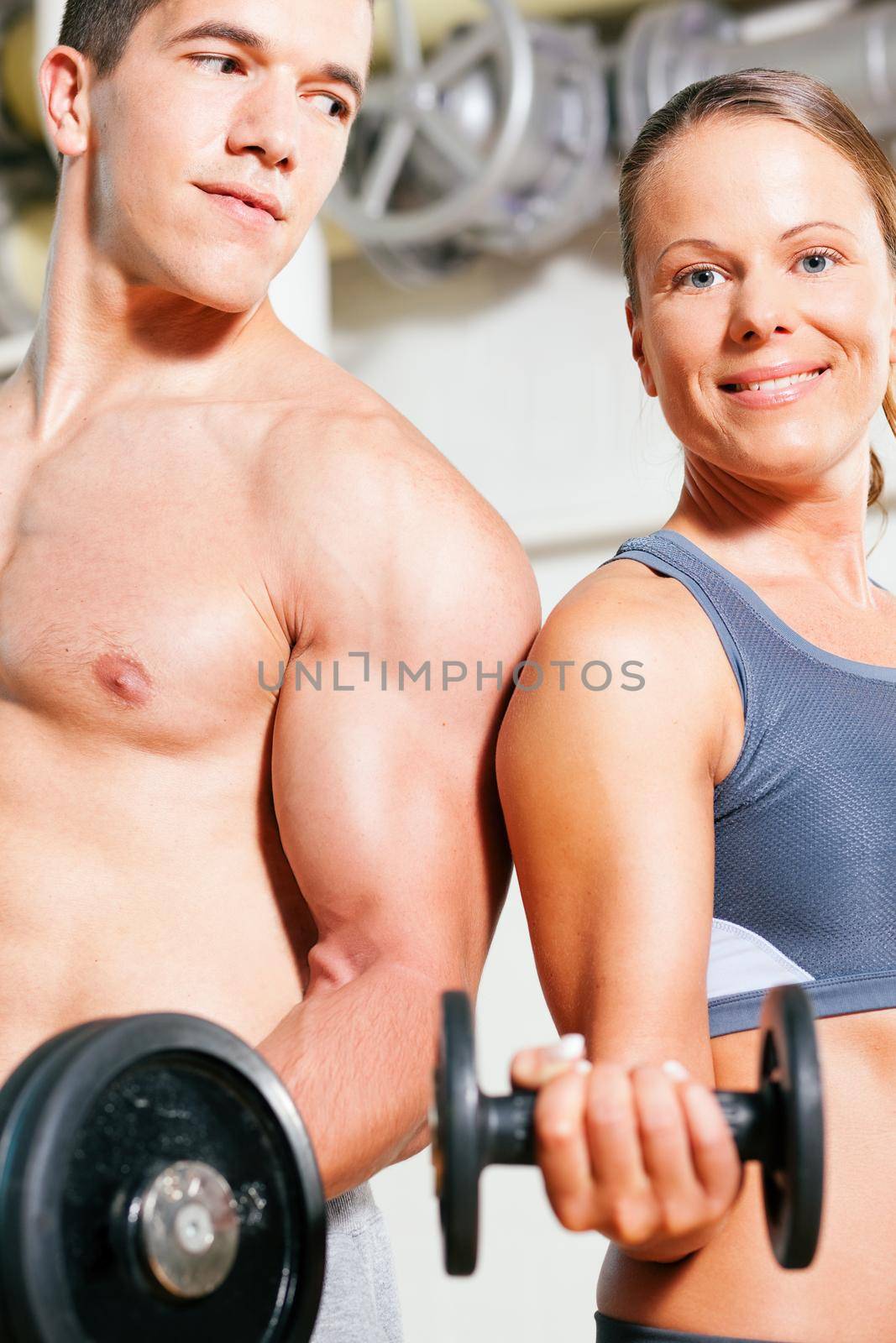 Couple exercising with dumbbells in a gym, focus on eyes of man and woman