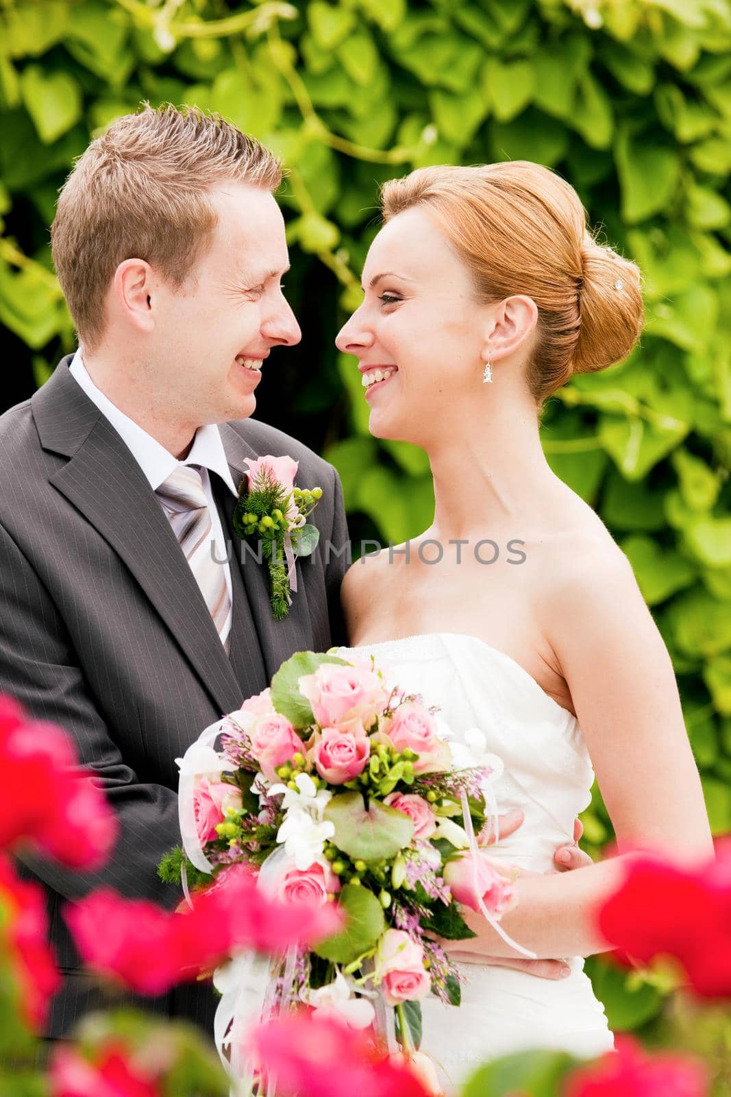 Wedding - groom and bride in a park, she is holding the bouquet of flowers