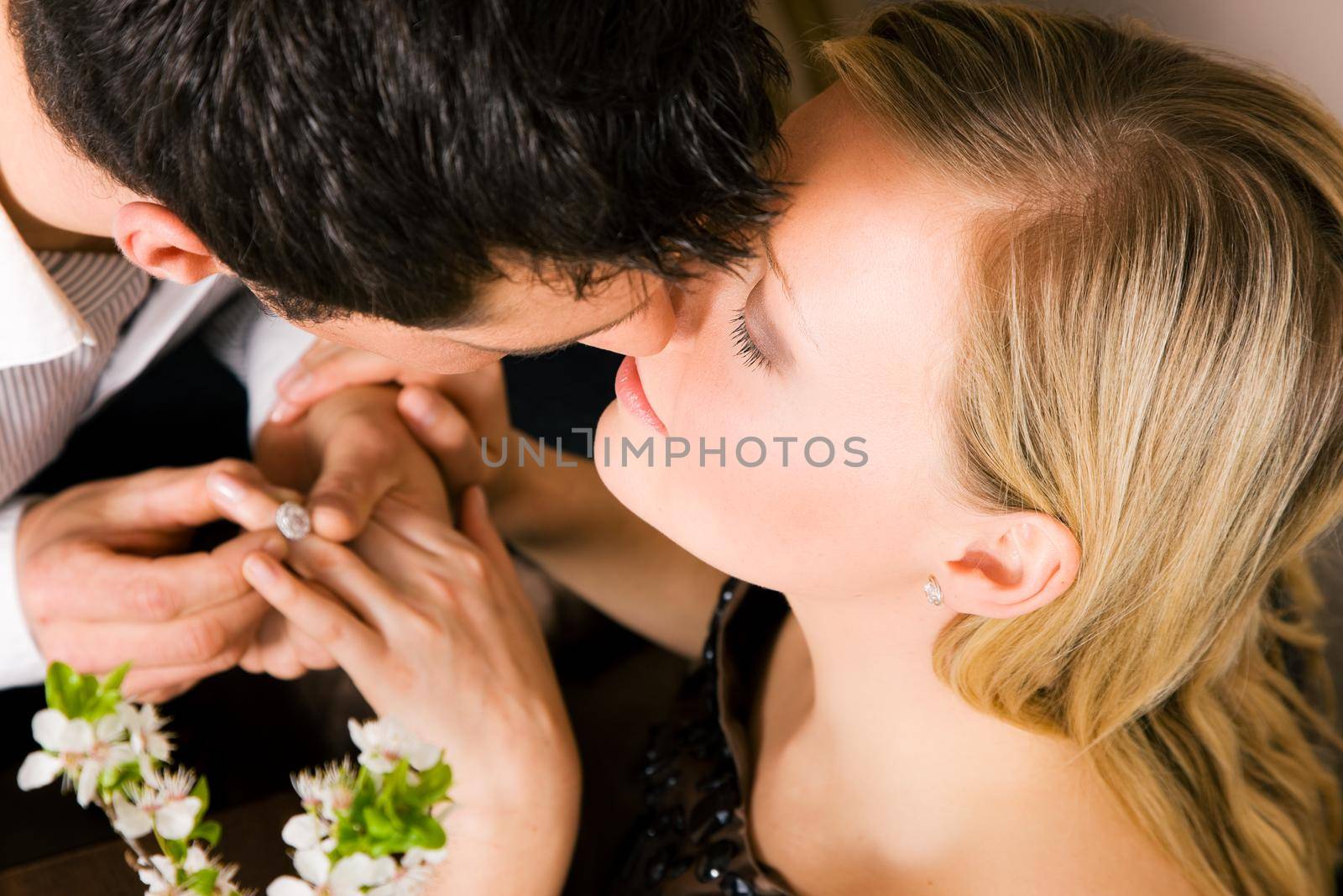 He is offering her the ring, she seems to be accepting with a kiss; focus on eyes