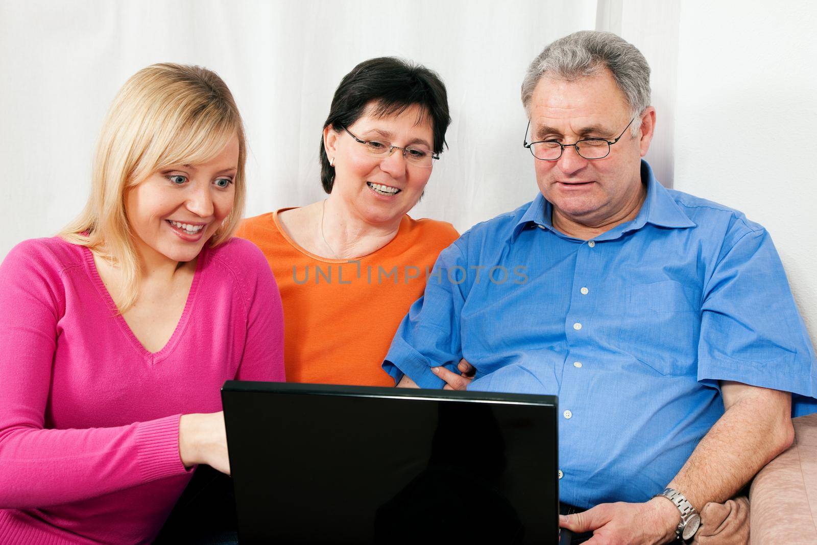 Family (parents and adult daughter) surfing the internet using a laptop
