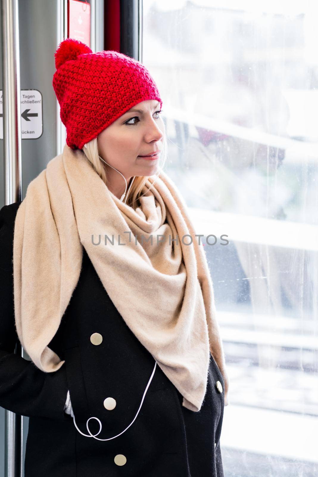 Woman standing inside a train near the door waiting for arrival by Kzenon