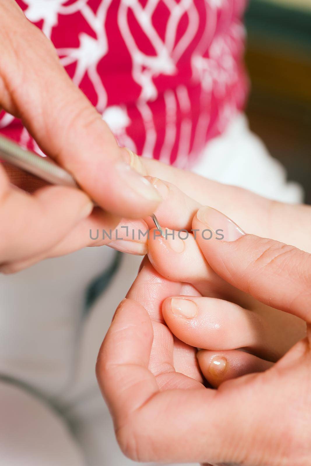 Woman practicing chiropody taking care of a feet; focus on hands and tool