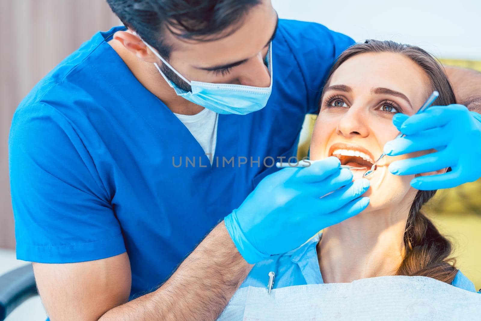 Young and beautiful woman looking with confidence at her reliable dentist during safe and painless dental treatment in a modern clinic