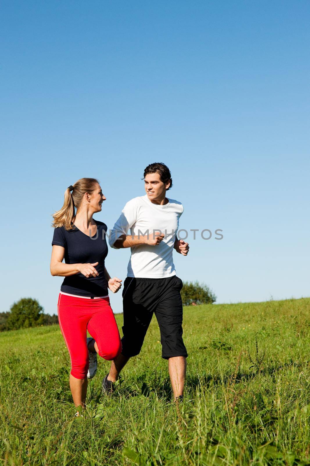 sport couple jogging an meadow in summer by Kzenon