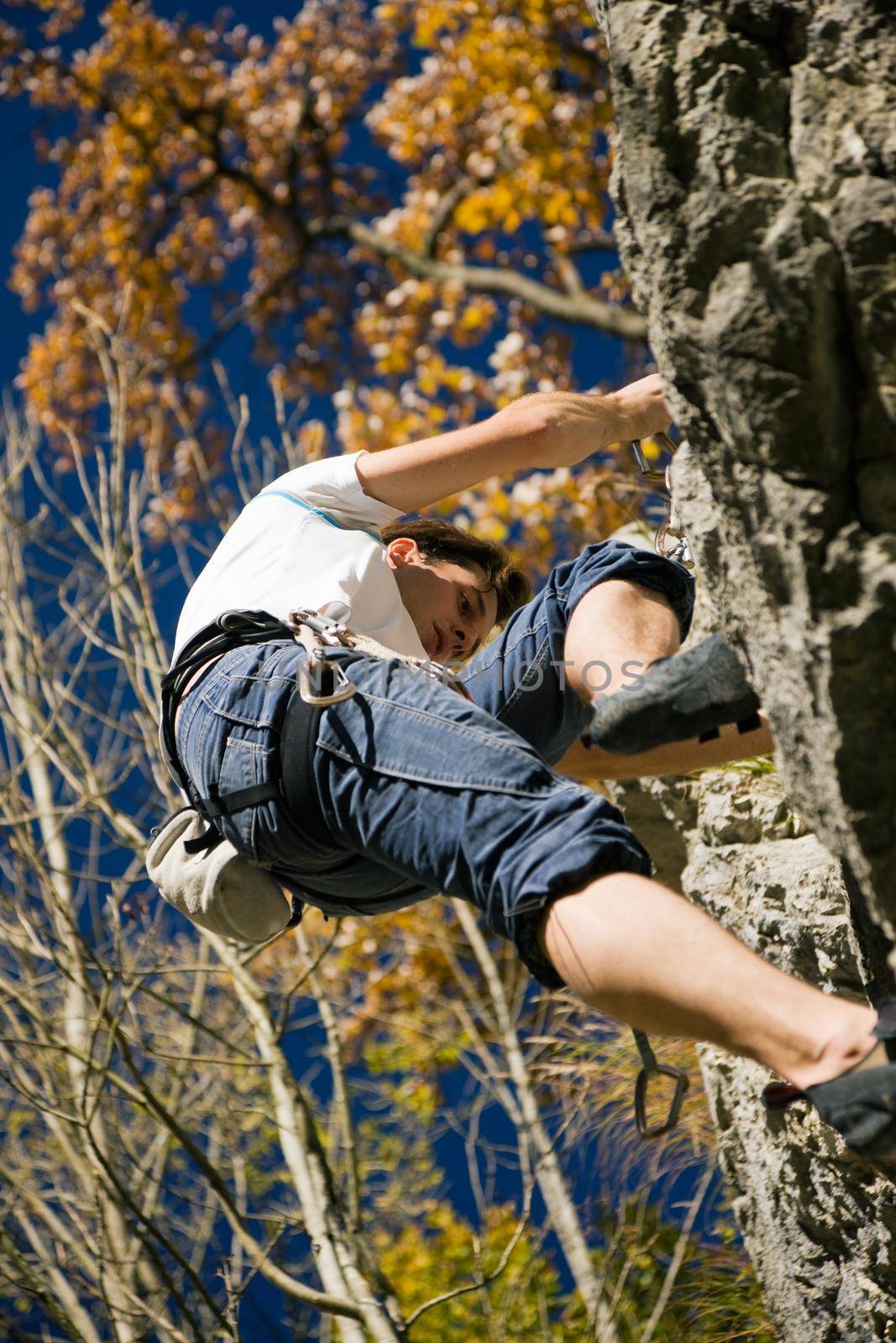 Man climbing a rock at a perfect clear autumn day in the mountains