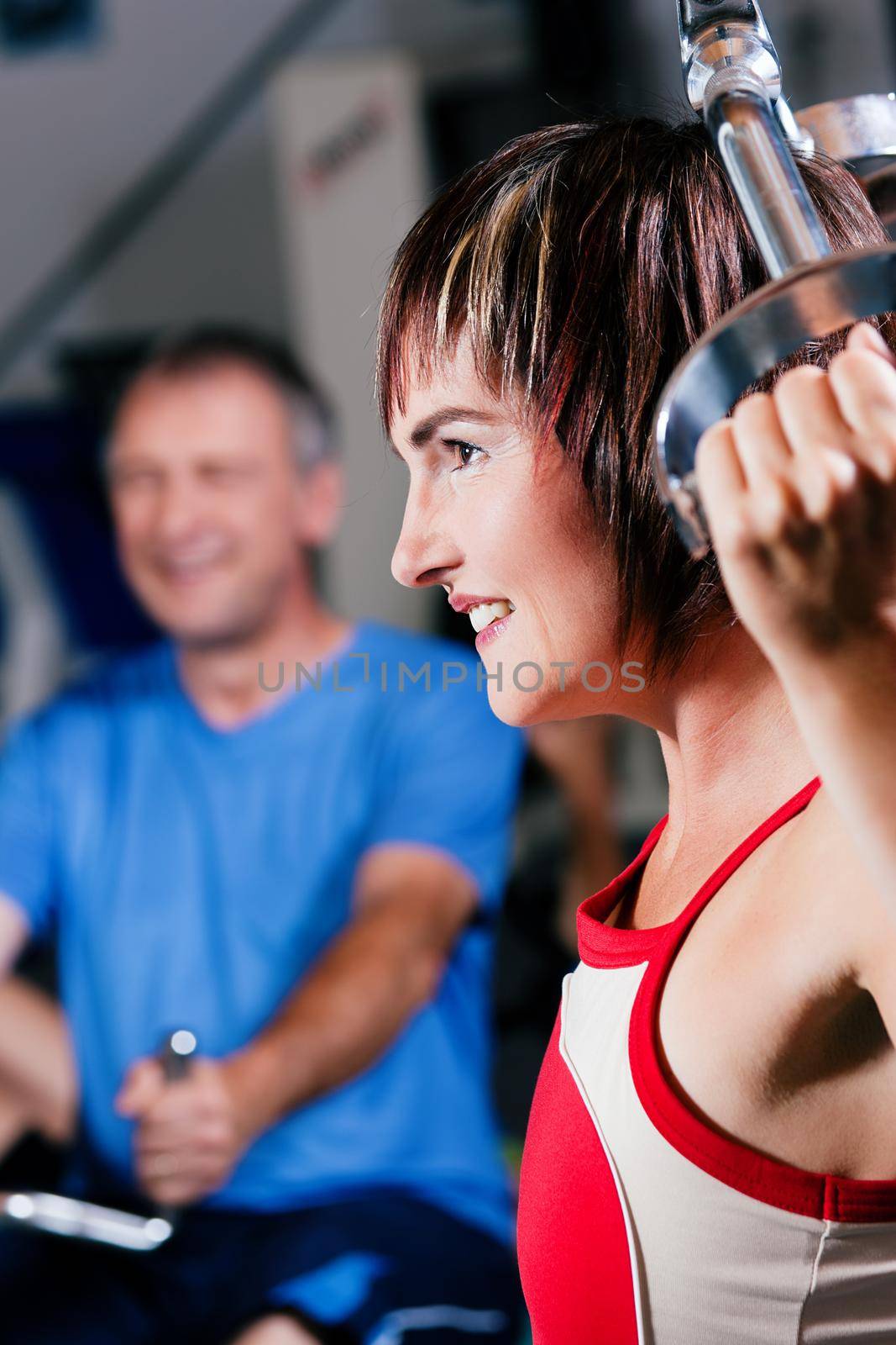 Mature woman in the gym lifting weights on a lat pull machine, exercising