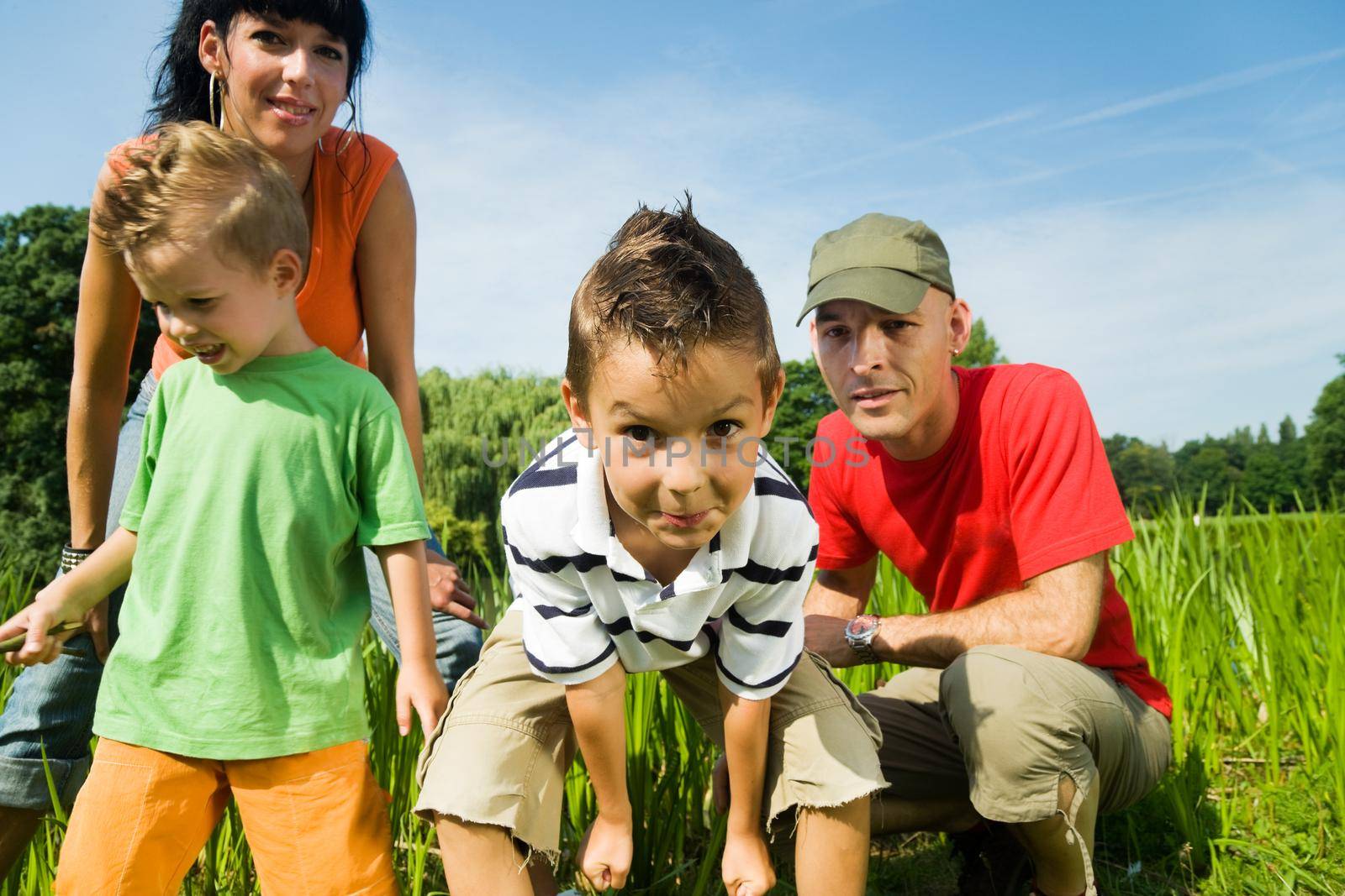 Family having fun, standing at the shore of a lake at a wonderful summer day (focus on the boy in front!)