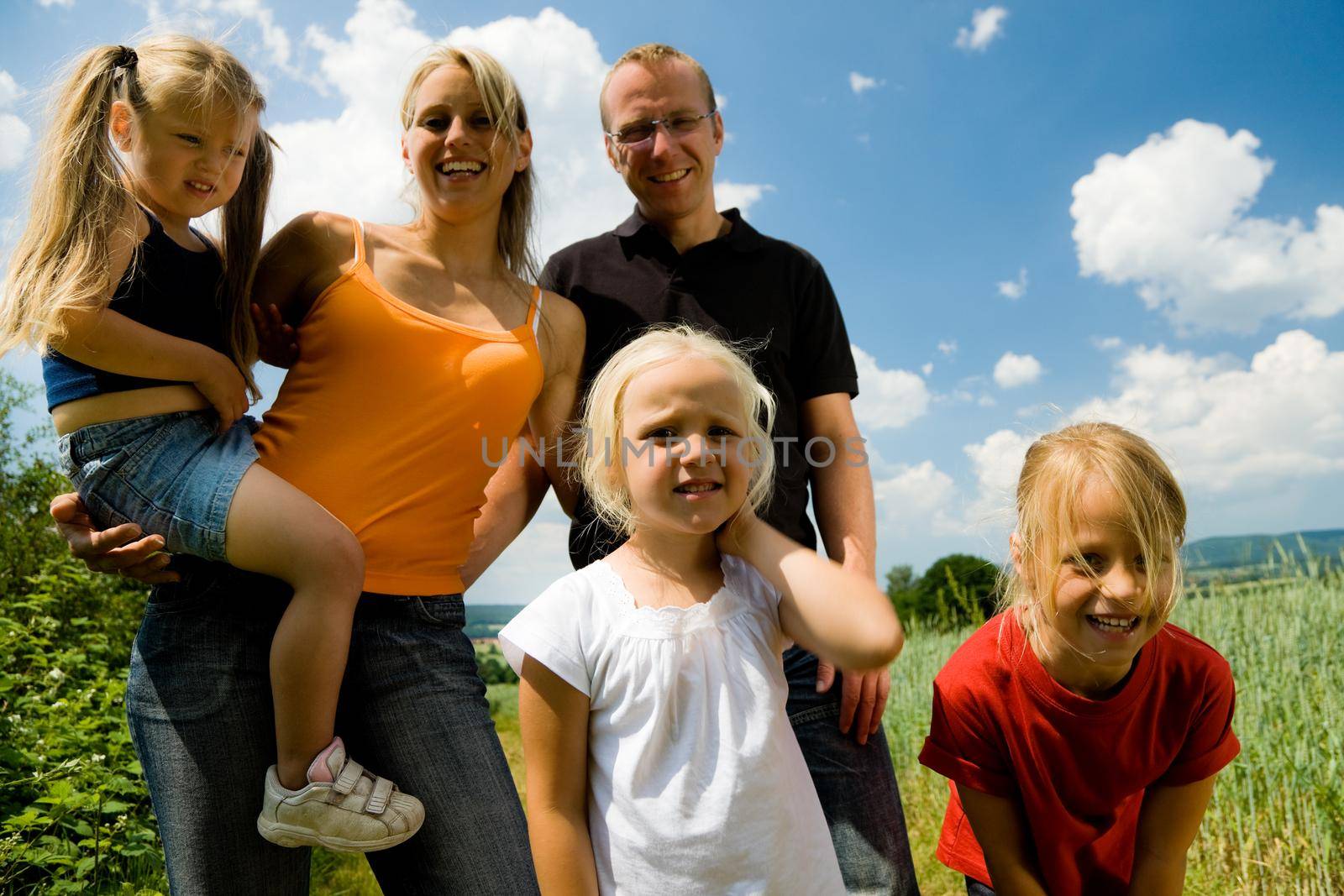 Family of five having an outdoor excursion on a summer day; focus on girls in front