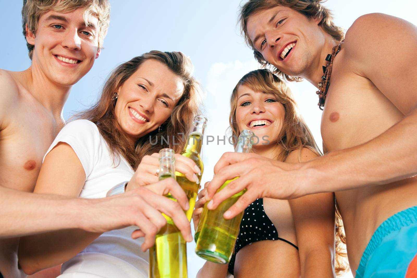 Group of four very beautiful people celebrating hot party on the beach in the summer of their lives - focus on faces