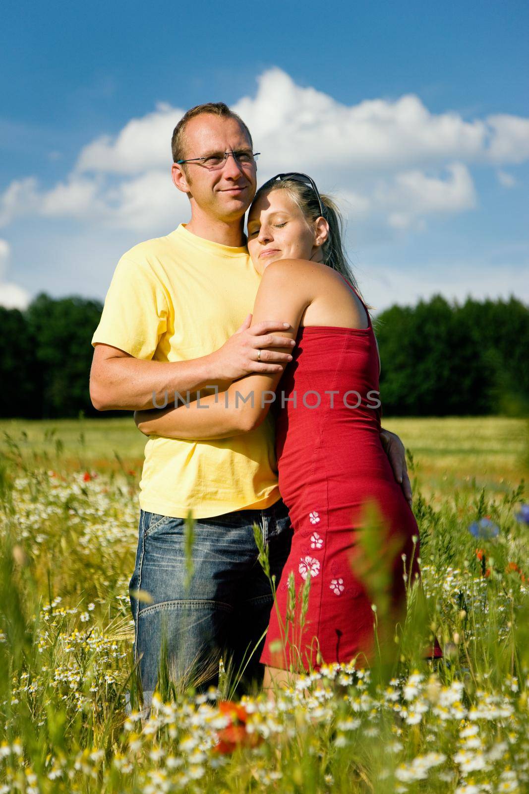 Couple in love embracing each other, standing in a field with wild flowers