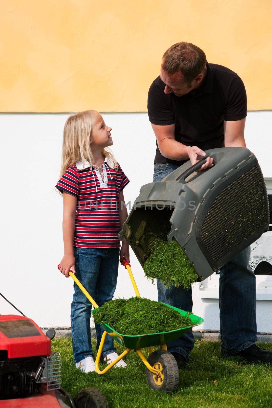 Father and daughter mowing lawn together