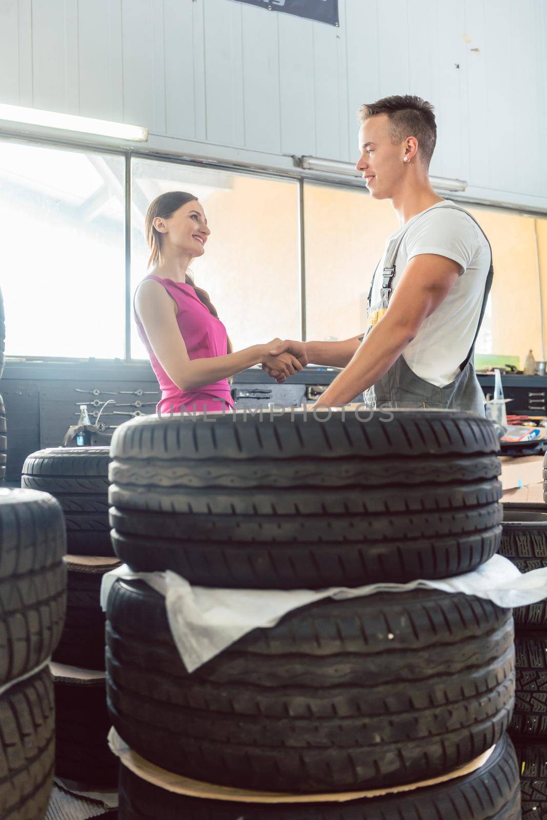 Handsome auto mechanic helping a customer to choose from various tires by Kzenon